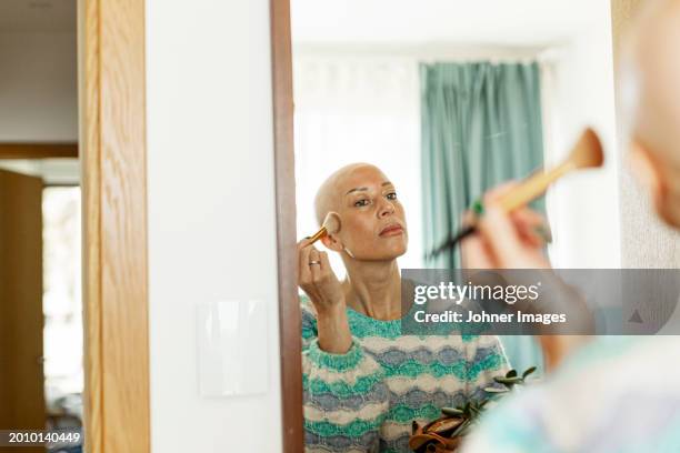 reflection of woman with cancer applying blusher on cheek at home - woman applying blush stock pictures, royalty-free photos & images