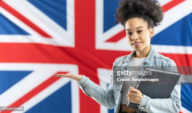 african american female student standing in front of british flag with school bag and laptop offering place for product or information. - slovakia people stock pictures, royalty-free photos & images