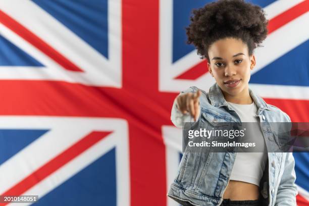 african american female english language student standing in front of a british flag pointing her hand at the camera. - slovakia people stock pictures, royalty-free photos & images