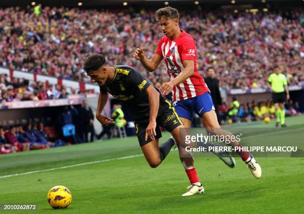 Las Palmas' Spanish defender Sergi Cardona falls down as he is challenged by Atletico Madrid's Spanish midfielder Marcos Llorente during the Spanish...