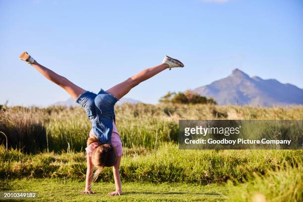 little girl doing cartwheels in a field outdoors in summer - cartwheel stock pictures, royalty-free photos & images