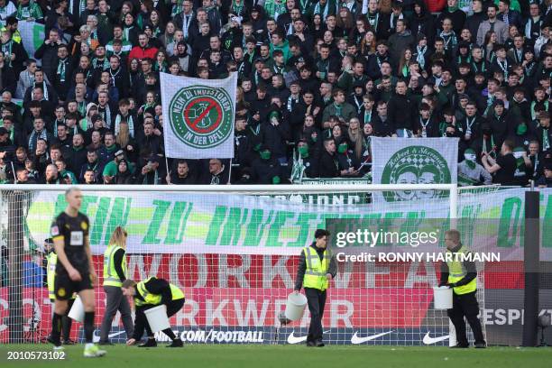 Staff collect tennis balls and chocolate coins thrown on to the pitch by fans protesting against the DFL during the German first division Bundesliga...