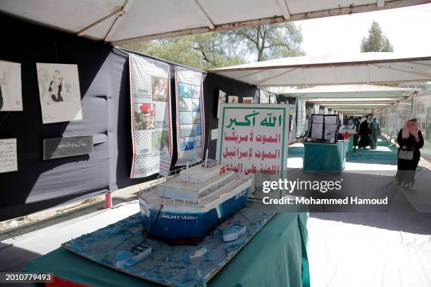 Women walk next to a mock model of the Houthi-hijacked Israeli Galaxy Leader cargo ship, displayed in solidarity with Palestinians and against the...