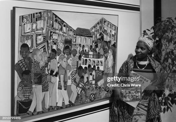 Malawian gallery visitor Ronalis Chirwa, holding the 'Art from Africa' catalogue, inspects 'Rush Hour - Lagos, Nairobi', by Kenyan artist Ancent Soi,...