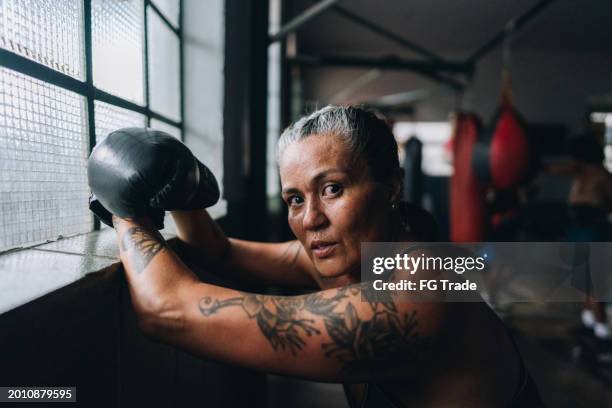 retrato de una mujer boxeadora cansada en un gimnasio de boxeo - kick boxing fotografías e imágenes de stock