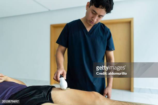 young physical therapist administers treatment - administers stock pictures, royalty-free photos & images