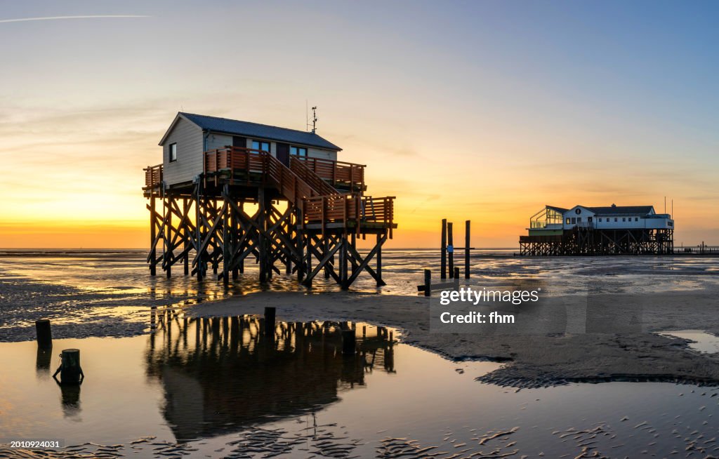Travel destination: Stilt houses on the beach in St. Peter Ording at sunset (Schleswig-Holstein, Germany)