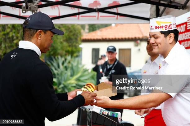 Tiger Woods of the United States gets an In-N-Out Burger after the eighth hole during a pro-am prior to The Genesis Invitational at Riviera Country...