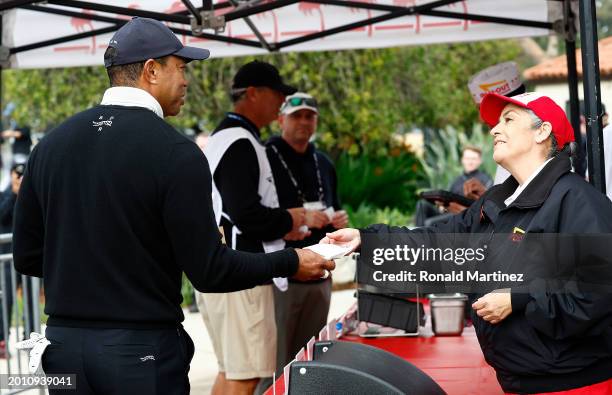 Tiger Woods of the United States gets an In-N-Out Burger after the eighth hole during a pro-am prior to The Genesis Invitational at Riviera Country...