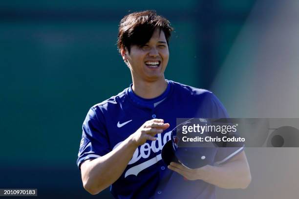Shohei Ohtani of the Los Angeles Dodgers laughs during workouts at Camelback Ranch on February 14, 2024 in Glendale, Arizona.