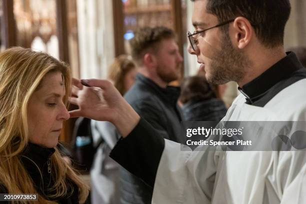 People get the sign of the cross placed on their forehead by a priest at St. Patricks Cathedral on Ash Wednesday on February 14, 2024 in New York...