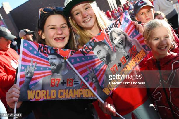 Fans hold up flags of Taylor Swift and Travis Kelce of the Kansas City Chiefs during the Kansas City Chiefs Super Bowl LVIII victory parade on...
