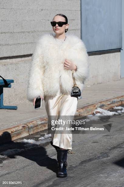 Guest is seen wearing a white coat, cream skirt, black boots, black sunglasses and carrying a black bag outside the Brandon Maxwell show during...