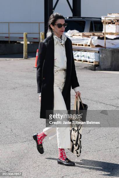 Guest is seen wearing a black coat, white shirt, white denim jeans, red socks, black loafers and carrying a black bag outside the Brandon Maxwell...