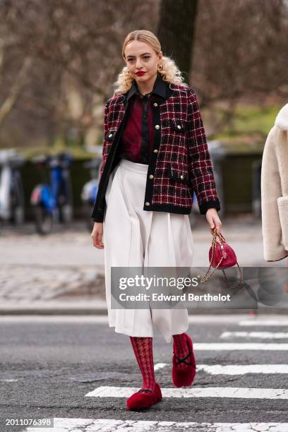 Guest wears golden earrings, red lipstick, a burgundy / red and black shirt, a black and burgundy checkered / checked pattern printed tweed jacket /...