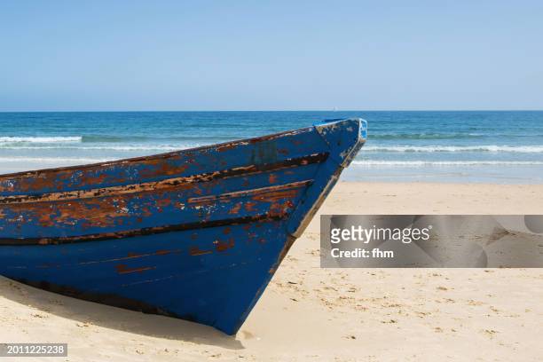 forgotten rowboat on the beach, partially buried in the sand - solitaire stock pictures, royalty-free photos & images