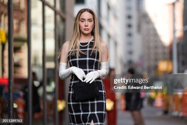 Sira Pevida wears a black and white checkered / checked pattern printed midi slit dress, white elbow long gloves, a black bag, outside Carolina...