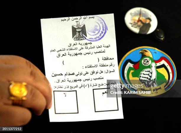 An Iraqi official displays a voting card which reads "In the name of God the merciful-The Iraq Republic-The supreme supervising council of the...