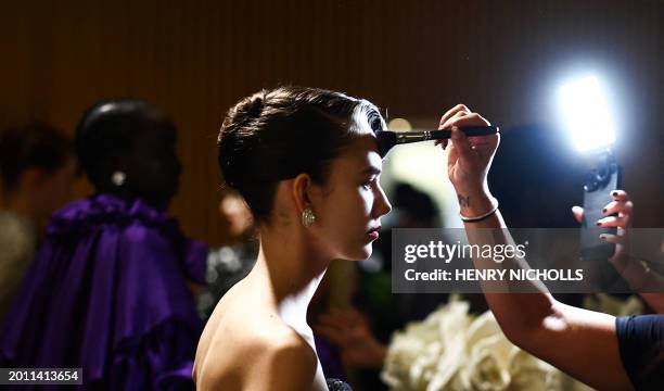 Model is prepared in the backstage ahead of a catwalk presentation by British designer Richard Quinn for his Autumn/Winter 2024 collection during...