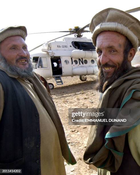 Two Afghan villagers smile while an UN helicopter delivers ballot boxes and voting material in the remote eastern Afghan village of Gas Ulia, 08...