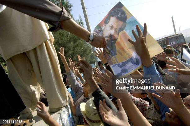 Afghan supporters of leading presidential candidate Yunus Qanooni grab posters bearing his picture prior to attending a Qanooni electoral rally at...