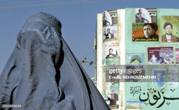 An Afghan woman passes by electoral posters of presidential candidates in Herat, 600 kilometers west of Kabul, 08 October 2004. Afghanistan is set to...