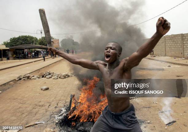 Togolese opposition activist brandishes a club in front of burning tyres as he shouts in a Lome neighborhood, 25 April 2005, one day after voters...