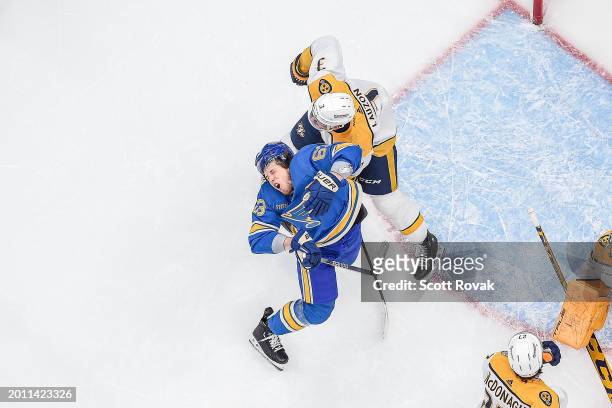 Jake Neighbours of the St. Louis Blues gets high sticked by Jeremy Lauzon of the Nashville Predators on February 17, 2024 at the Enterprise Center in...