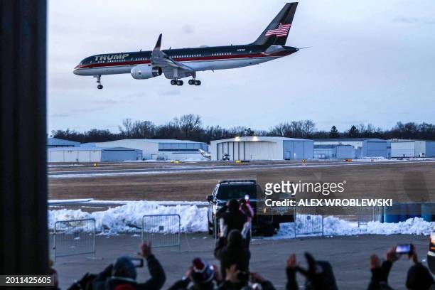 Supporters of former US President and 2024 presidential hopeful Donald Trump cheer as his plane, Trump Force One, lands outside a "Get Out the Vote"...
