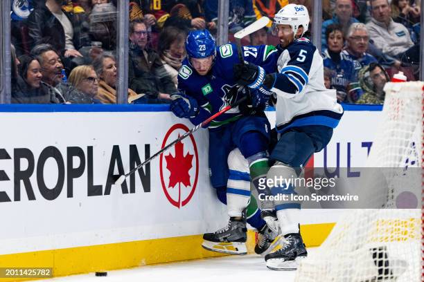 Vancouver Canucks center Elias Lindholm and Winnipeg Jets defenseman Brenden Dillon tangle up in the boards during an NHL game between the Winnipeg...