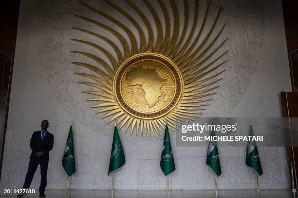 Security guard stands next to an AU logo at the entrance of the main plenary hall during the second day of the 37th Ordinary Session of the Assembly...