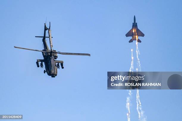 Singaporean Air Force's F15SG fighter jet and Apache helicopter perform during a preview of the Singapore Airshow in Singapore on February 18, 2024.
