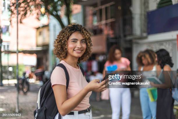 outdoors portrait of young student using smartphone - depoimento imagens e fotografias de stock