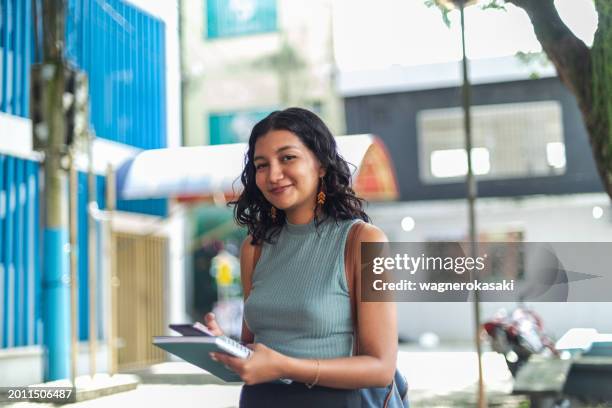 ritratto all'aperto di giovane studente che usa lo smartphone - tre quarti anteriore foto e immagini stock