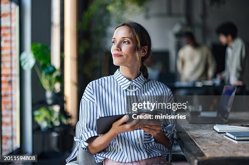 Professional Woman with Tablet Looking Thoughtful in Office Professional Woman with Tablet Looking Thoughtful in Office