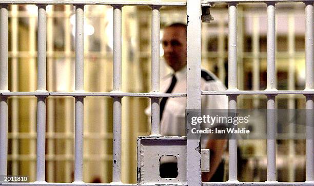 Prison guard at HMP Pentonville stands behind a locked gate May 19, 2003 in London. A new report from the Prison Reform Trust says overcrowding in...