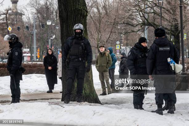 Police watch people as they lay flowers at a monument to victims of political repression to honor Russian opposition leader Alexei Navalny the day...