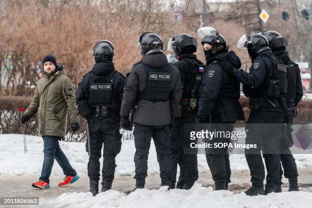 Police watch people as they lay flowers at a monument to victims of political repression to honor Russian opposition leader Alexei Navalny the day...