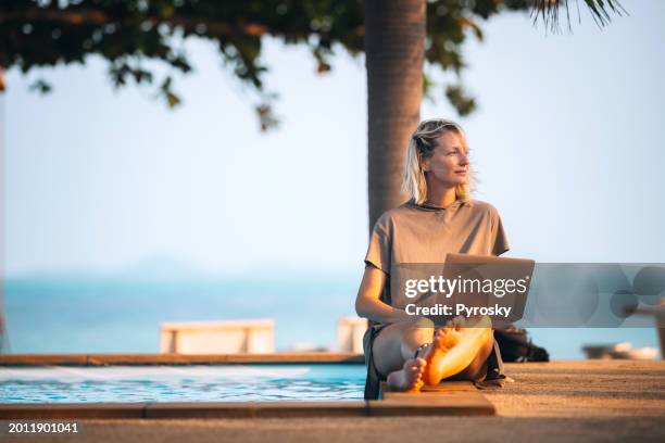 une femme travaille à distance au bord de la piscine - télétravail photos et images de collection