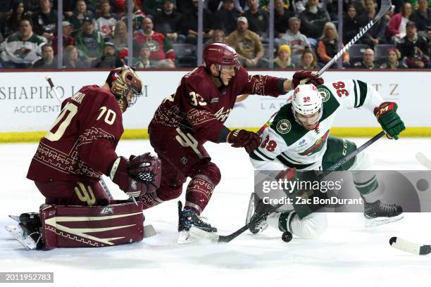 Ryan Hartman of the Minnesota Wild skates for a loose puck against Travis Dermott and goaltender Karel Vejmelka of the Arizona Coyotes during the...