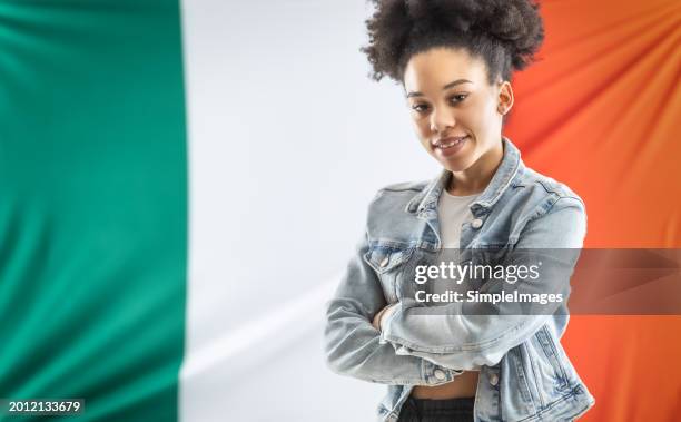 african american female student stands with crossed arms in front of italian flag. - national teacher stock pictures, royalty-free photos & images