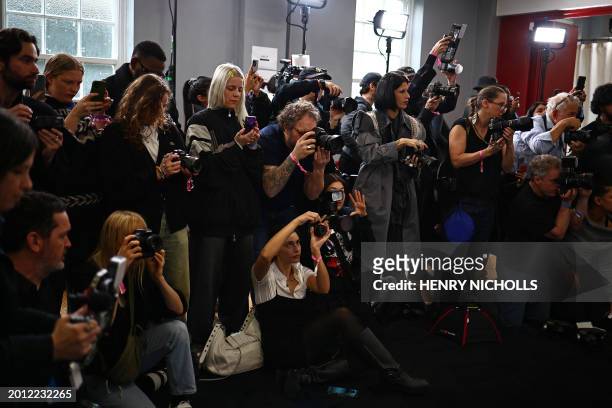 Members of the media take photographs of models back-stage ahead of the catwalk presentation for British fashion label JW Anderson for their...