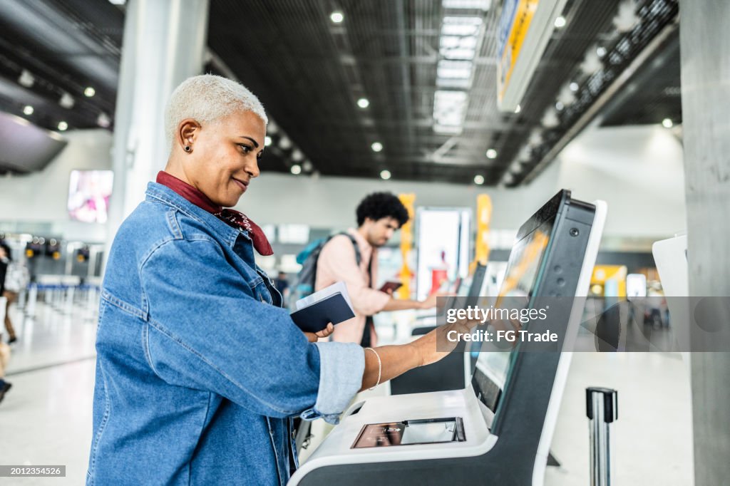 Mujer madura que usa la máquina de autoservicio de check-in en el aeropuerto