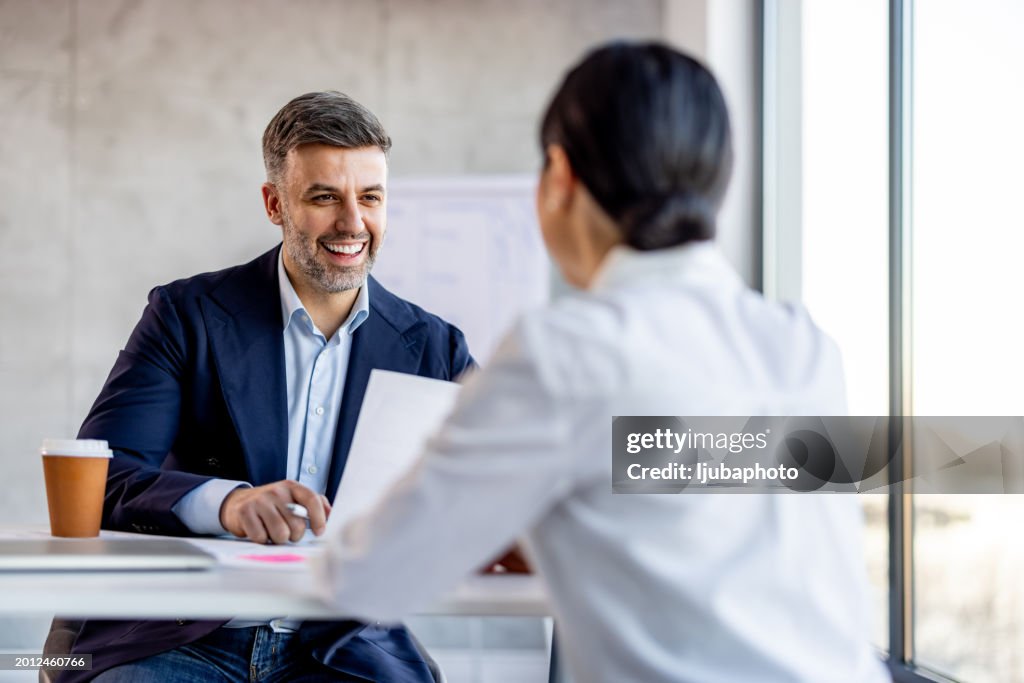 Cheerful businessman having a meeting with a shortlisted job applicant in a modern workplace.