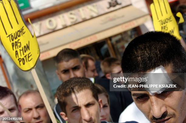 People hold "touche pas à mon pote" signs during a demonstration organized by "SOS Racisme" against the violence by French far-right party Front...