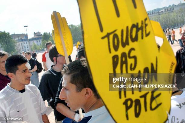 People hold "touche pas à mon pote" signs during a demonstration organized by "SOS Racisme" against the violence by French far-right party Front...