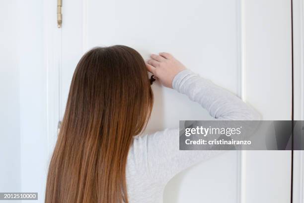 young woman looking through the viewer of a door - cristinairanzo stock pictures, royalty-free photos & images