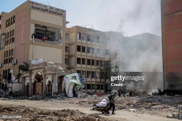 Young Palestinian pulls a wheel cart past the heavily damaged building of Al-Azhar University in Gaza City on February 15 amid the continuing war...