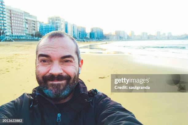 adult man smiling taking a selfie on the beach - adulto maduro stock pictures, royalty-free photos & images