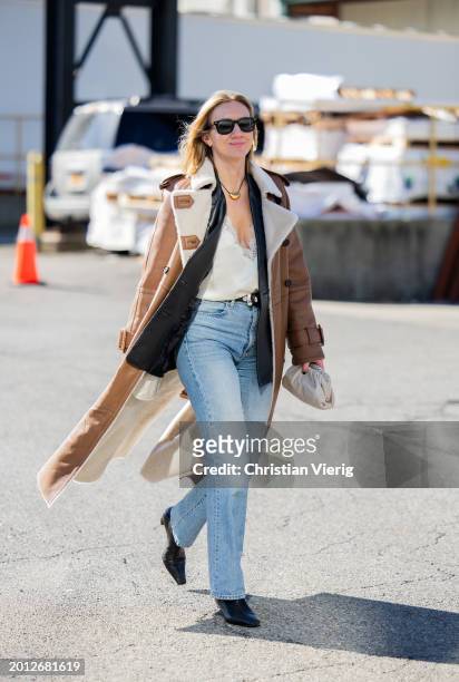 Lisa Aiken wears brown shearling coat, denim jeans, mini Bottega Veneta bag outside Brandon Maxwell on February 14, 2024 in New York City.